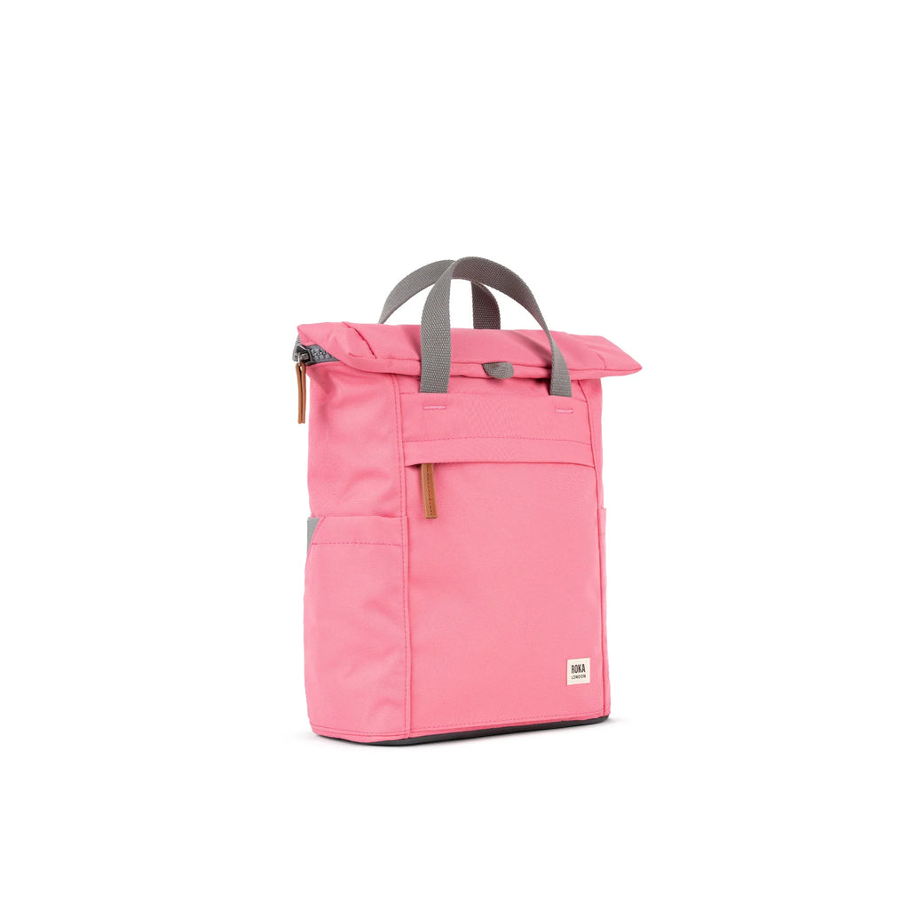Pink ROKA backpack with gray straps, featuring a roll-top closure and front pocket.