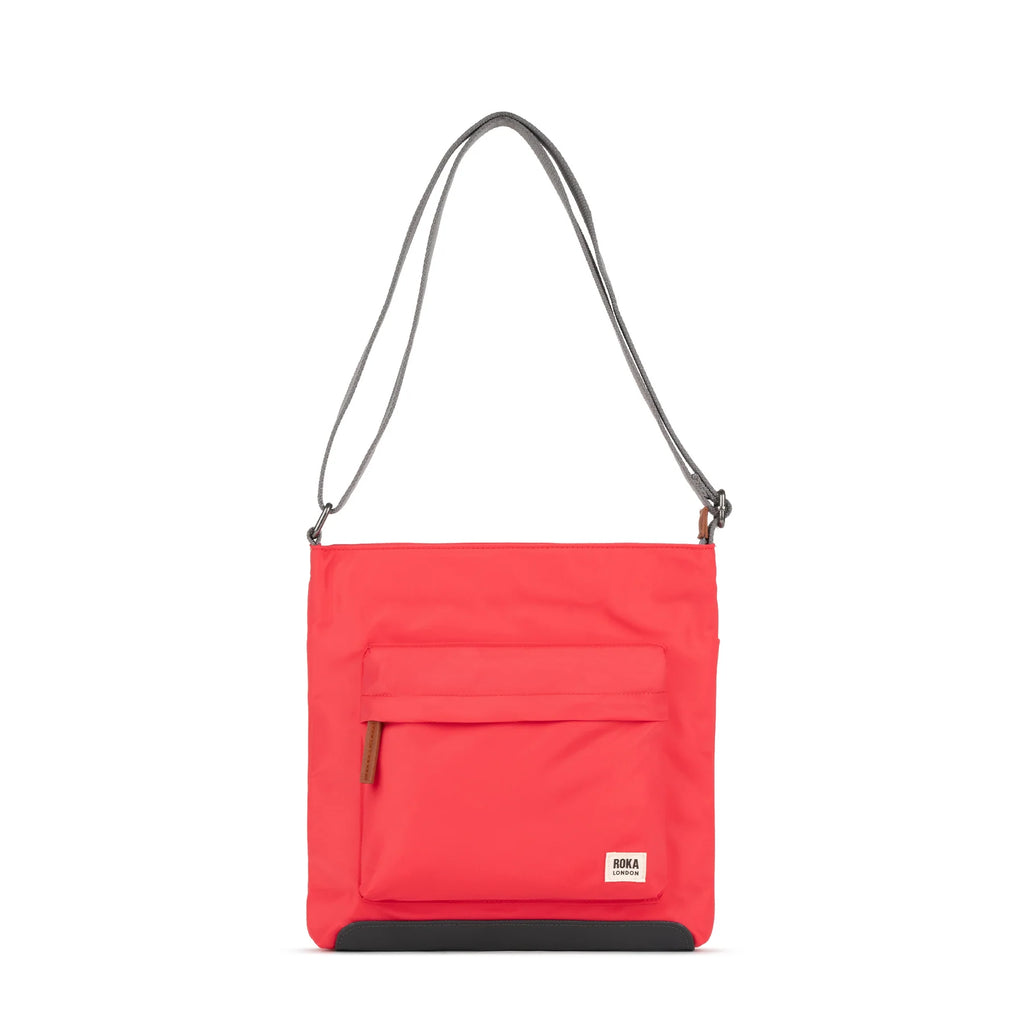 ROKA red crossbody bag with a front pocket and gray strap, featuring a stylish and minimal design.