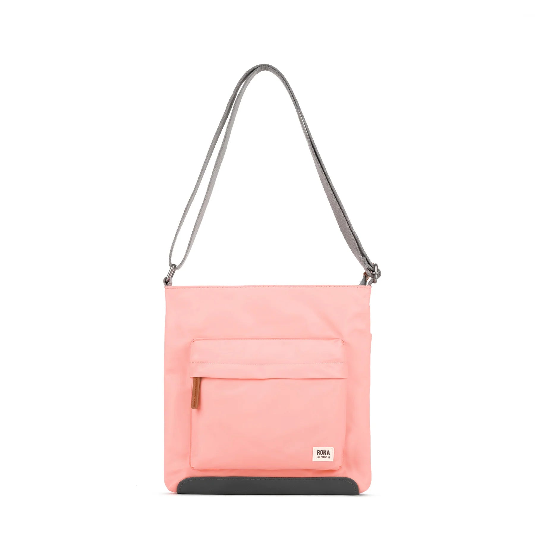 ROKA pink crossbody bag with a front pocket and gray strap on a white background.