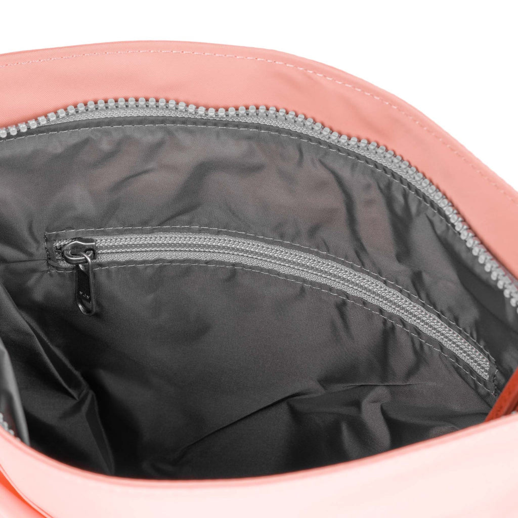 Interior of a ROKA bag, showing a peach exterior and a grey zipper pocket lined with smooth fabric.