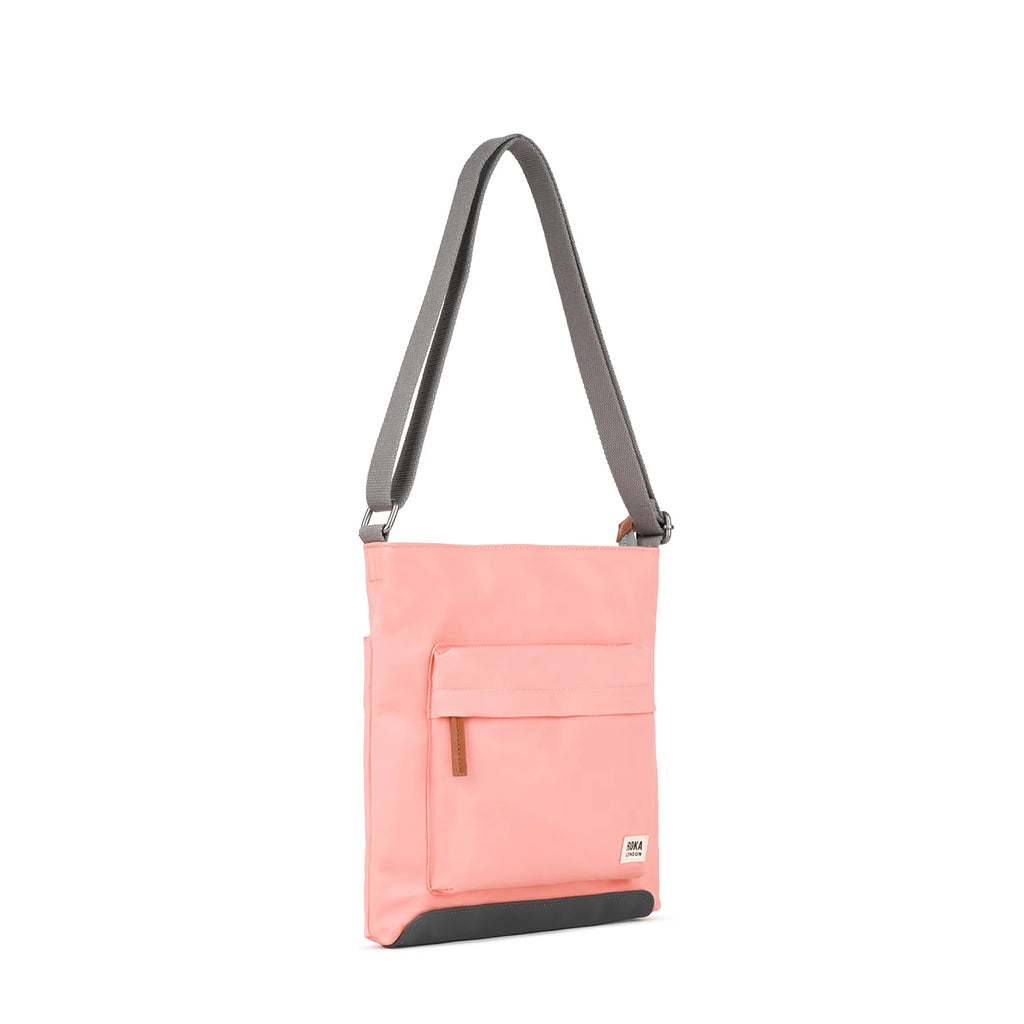 ROKA pink crossbody bag with a grey strap and front pocket, stylish and functional.