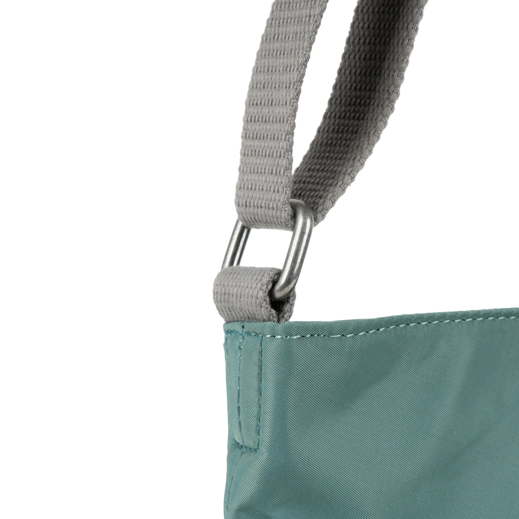 Close-up of a teal nylon handbag's shoulder strap and top. The strap is gray fabric with silver metal hardware.