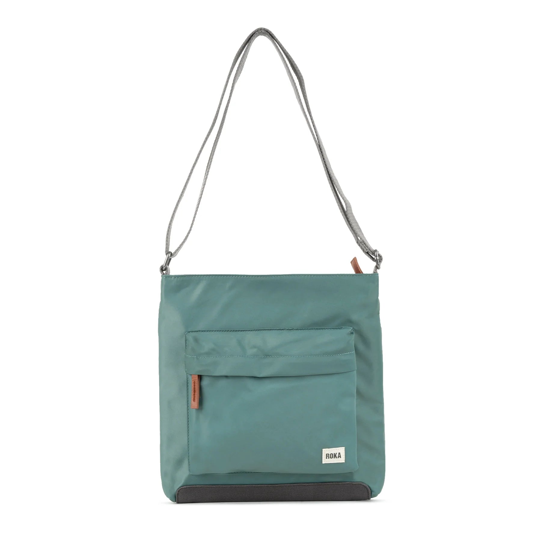 Teal crossbody bag with gray straps, a front pocket, and a dark gray bottom. The bag has a small "ROKA" label.