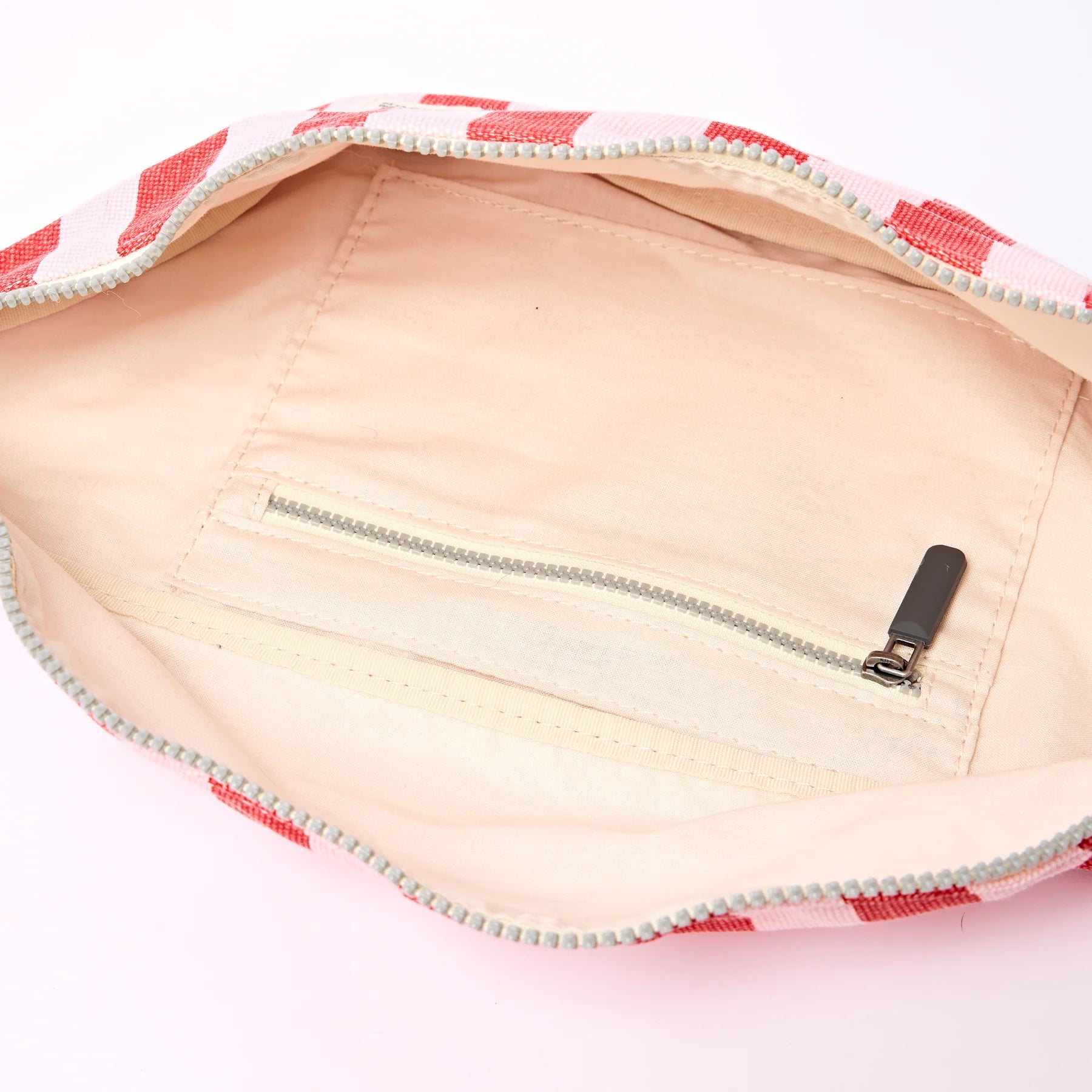 Close-up of a zipper on a pink and white checkered fabric with a white background.