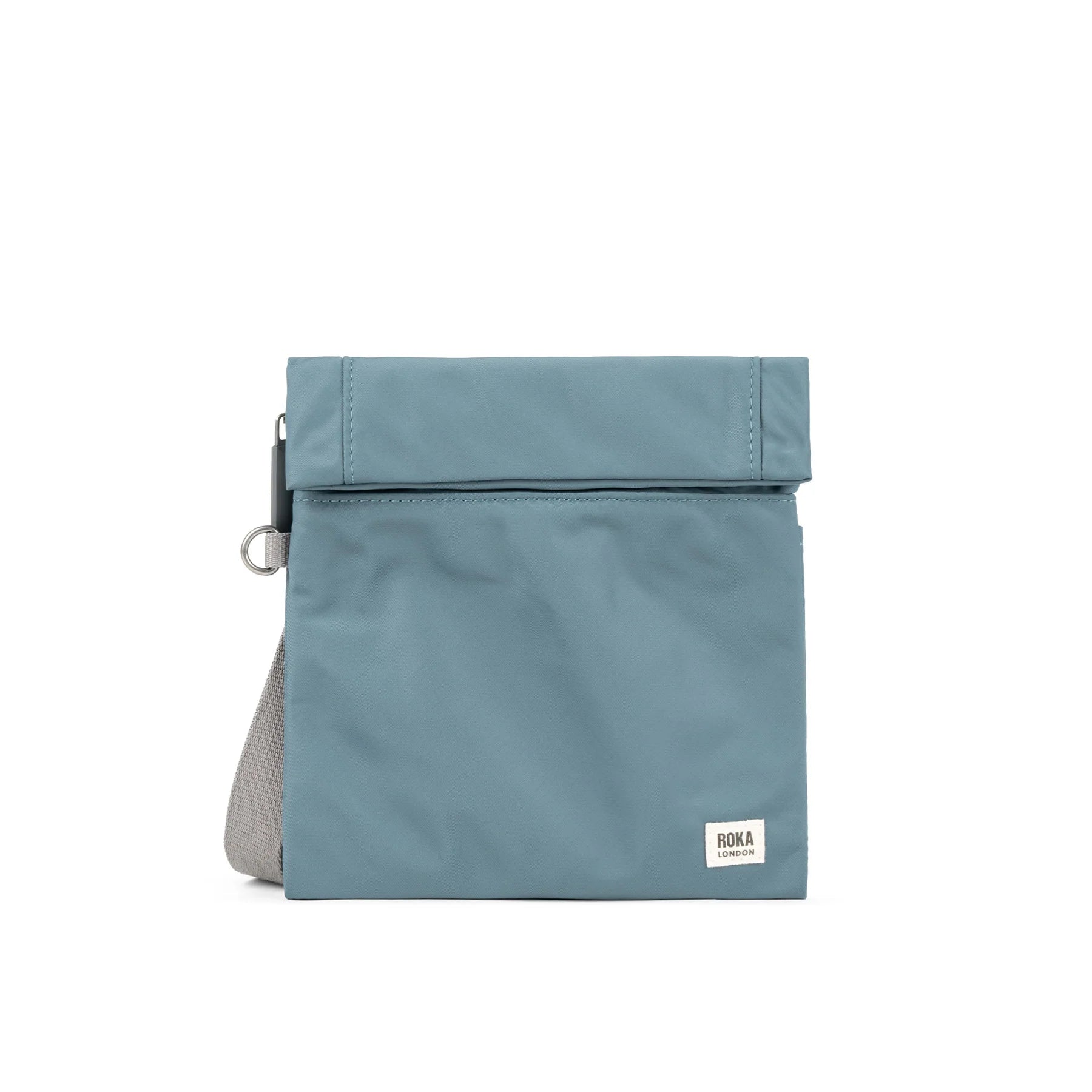 A light blue ROKA bag with a fold-over top and a shoulder strap, designed for style and functionality.