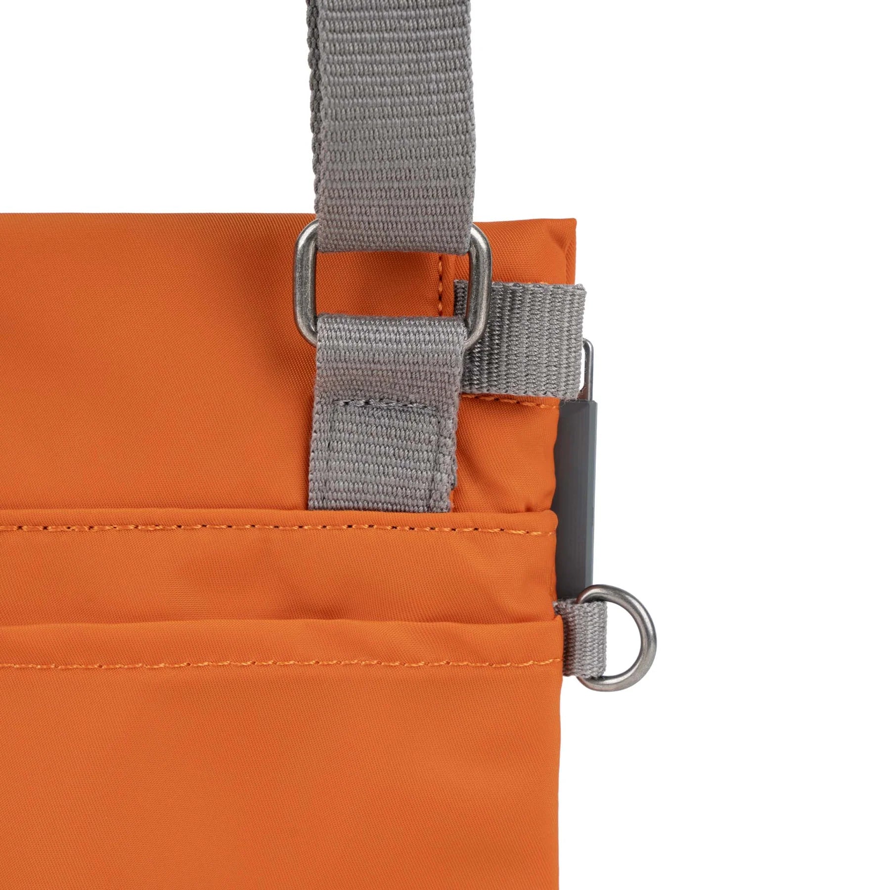 An orange ROKA bag with a gray strap and clip, showcasing its sleek design and functional pockets.