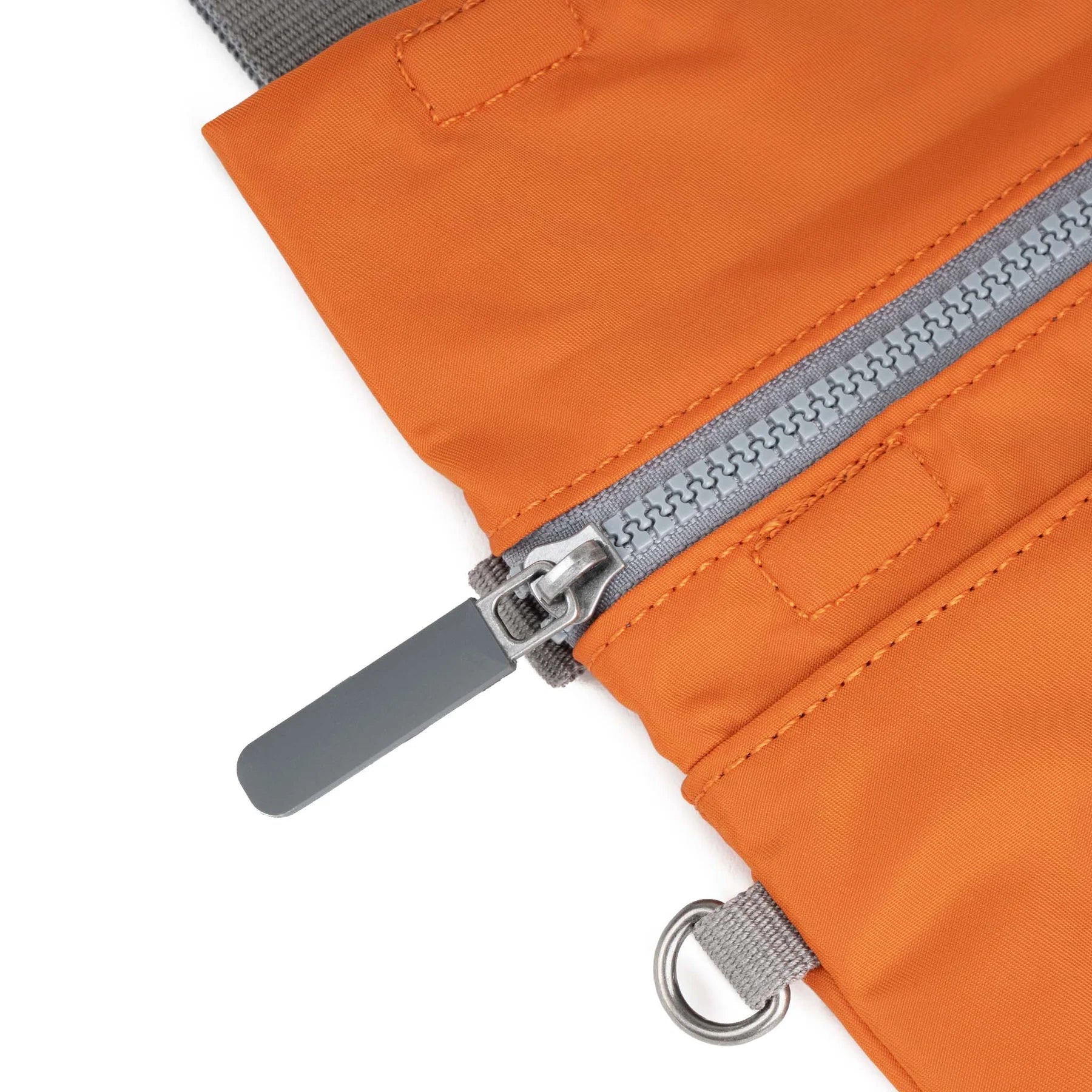 Close-up of an orange ROKA pouch featuring a gray zipper and metal pull tab.