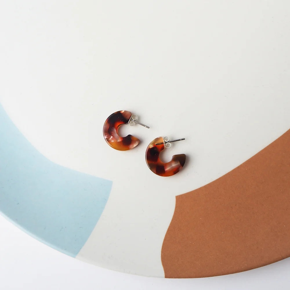 Pair of tortoiseshell-patterned resin hoop earrings with silver posts.