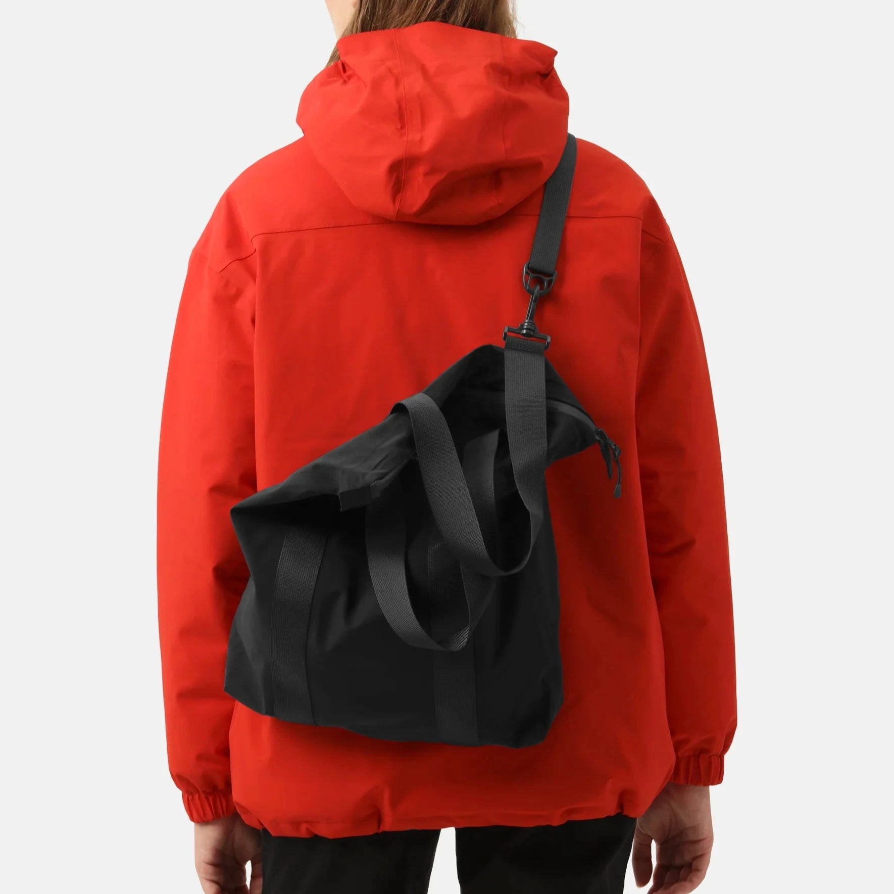 Rear view of person wearing a red hooded jacket with a black tote bag slung over one shoulder.