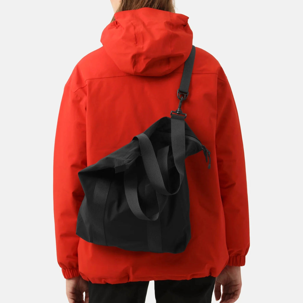 Rear view of person wearing a red hooded jacket with a black tote bag slung over one shoulder.