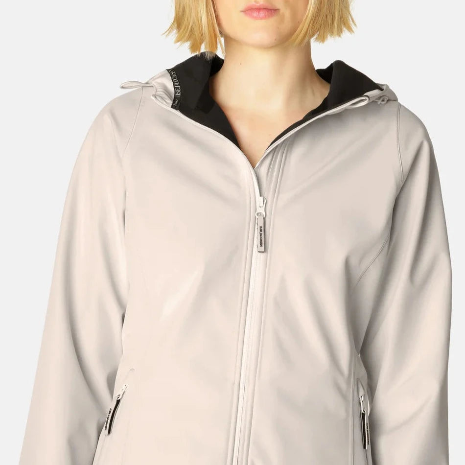 Cream-colored softshell jacket with black hood lining, zip closure, and subtle branding. Smooth, matte texture.