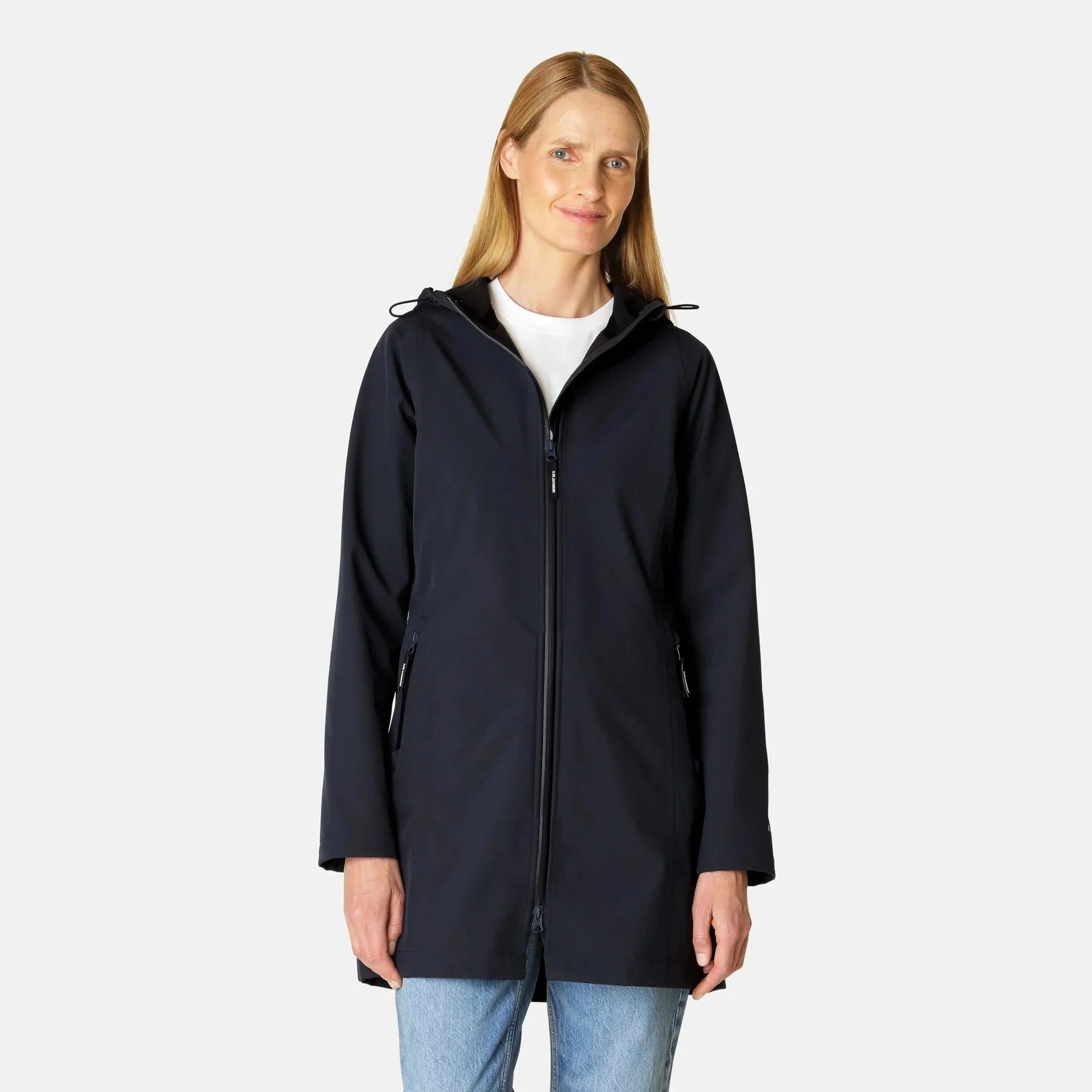 Woman in navy blue softshell hooded jacket with zip closure, long sleeves, and hip-length cut. The jacket has a smooth texture.