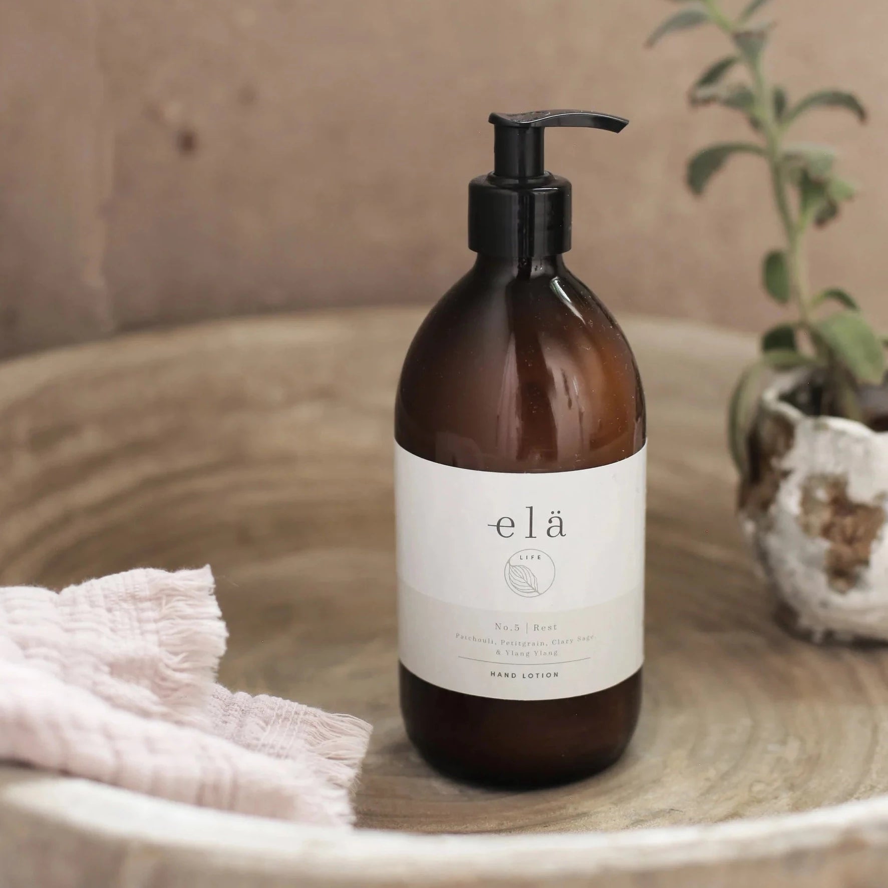 Amber glass bottle of elá Life No.5 Rest hand lotion with a black pump top.