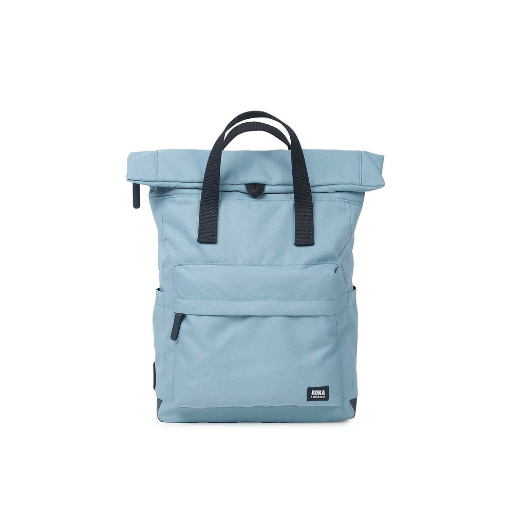 Light blue roll-top backpack by ROKA with black straps and front pocket. Stylish and functional for everyday use.