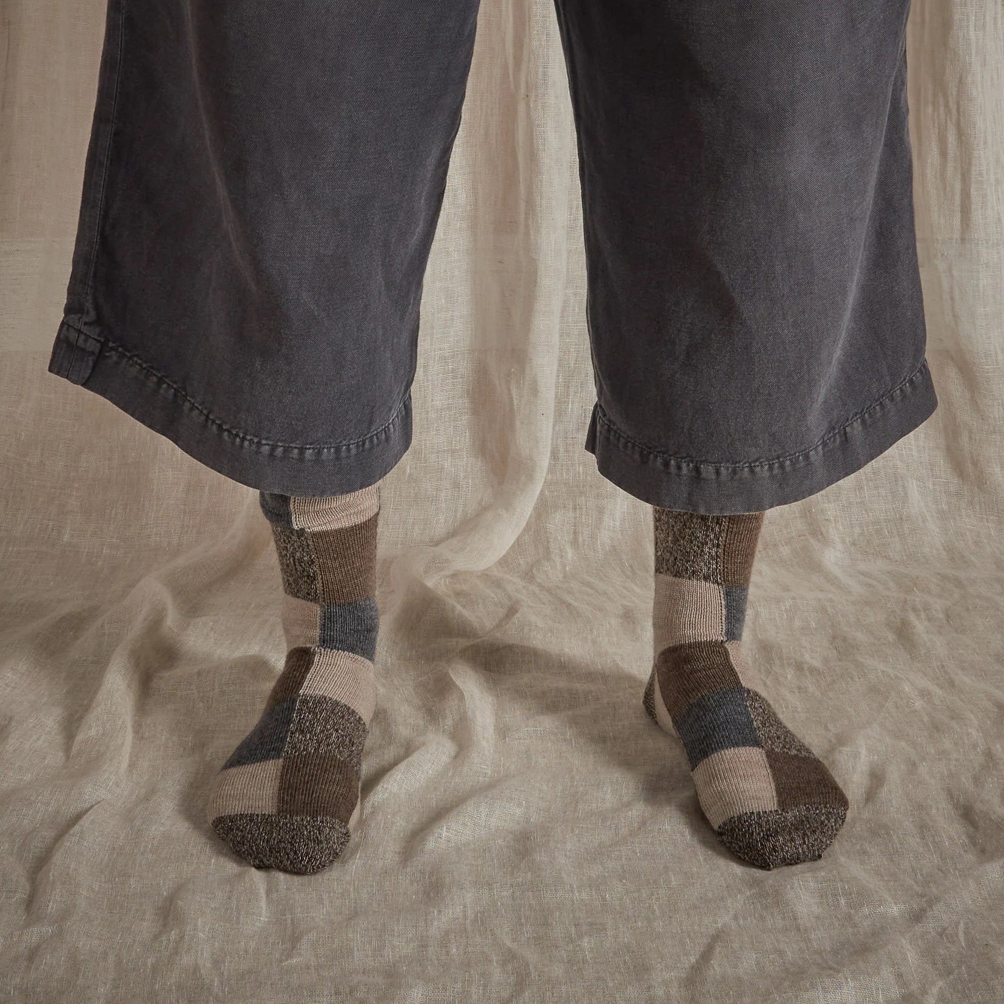 Pair of wool socks with a patchwork design in beige, brown, and gray.