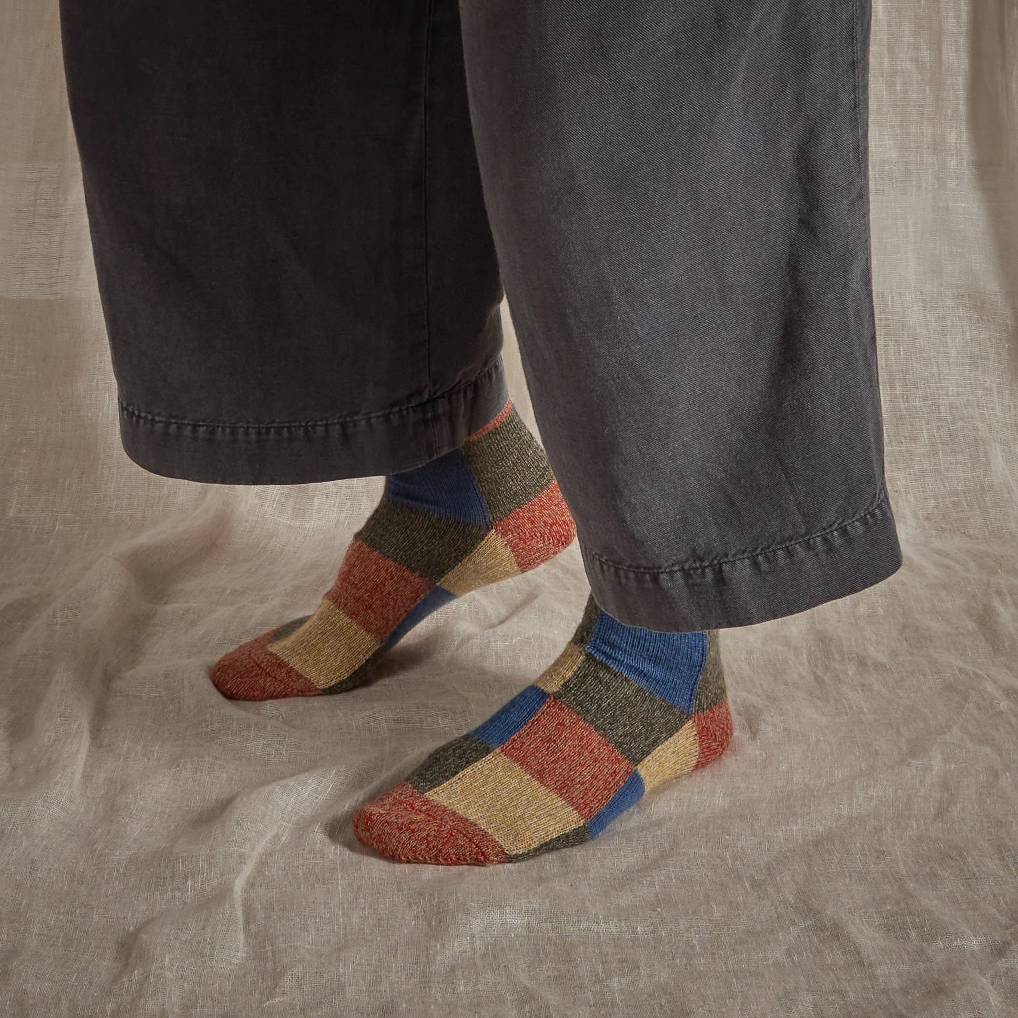 Pair of multicolored patchwork socks in red, beige, blue, and green.  The socks have a large checkered pattern.