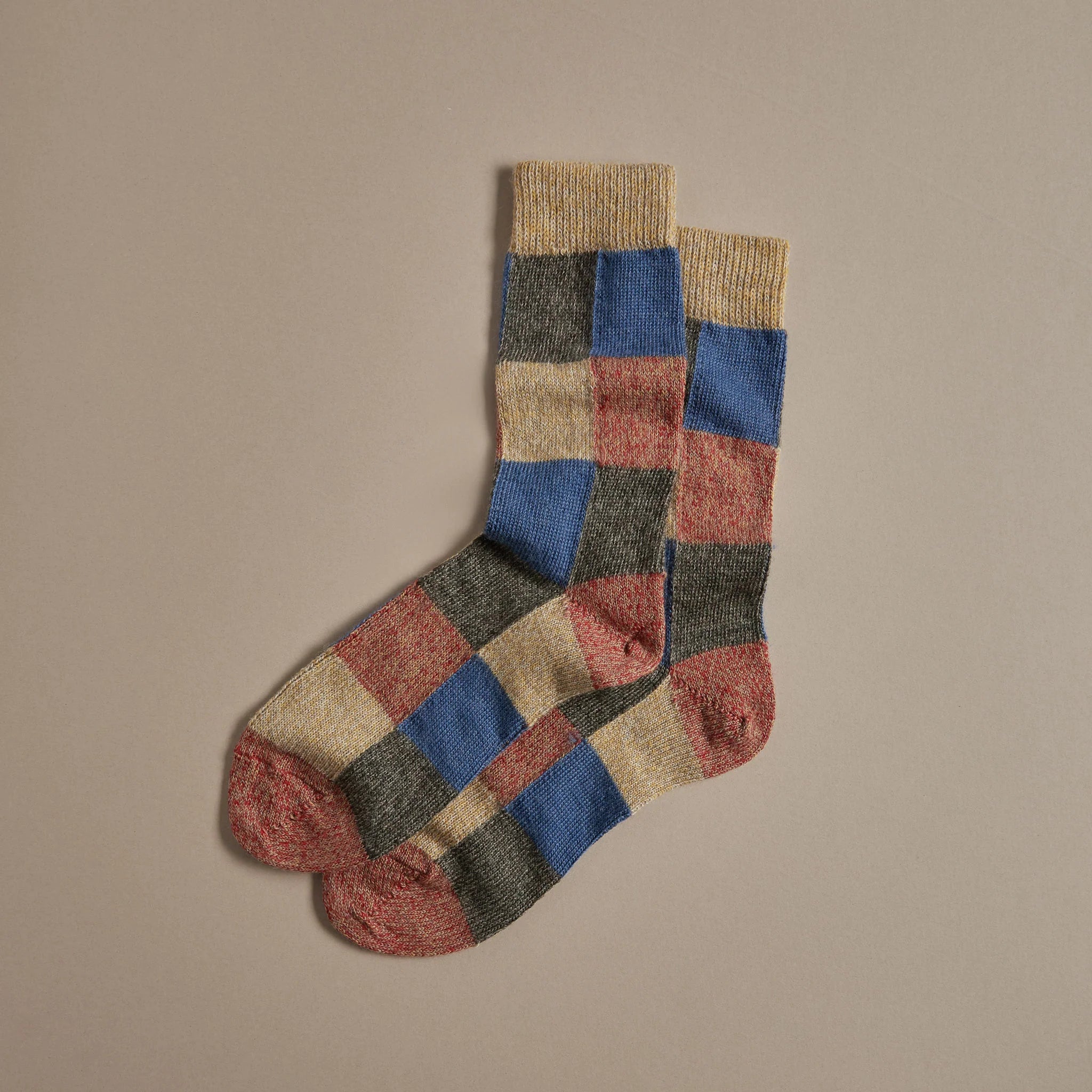 Pair of multicolored wool socks with a checkered pattern in shades of beige, blue, red, and dark green.