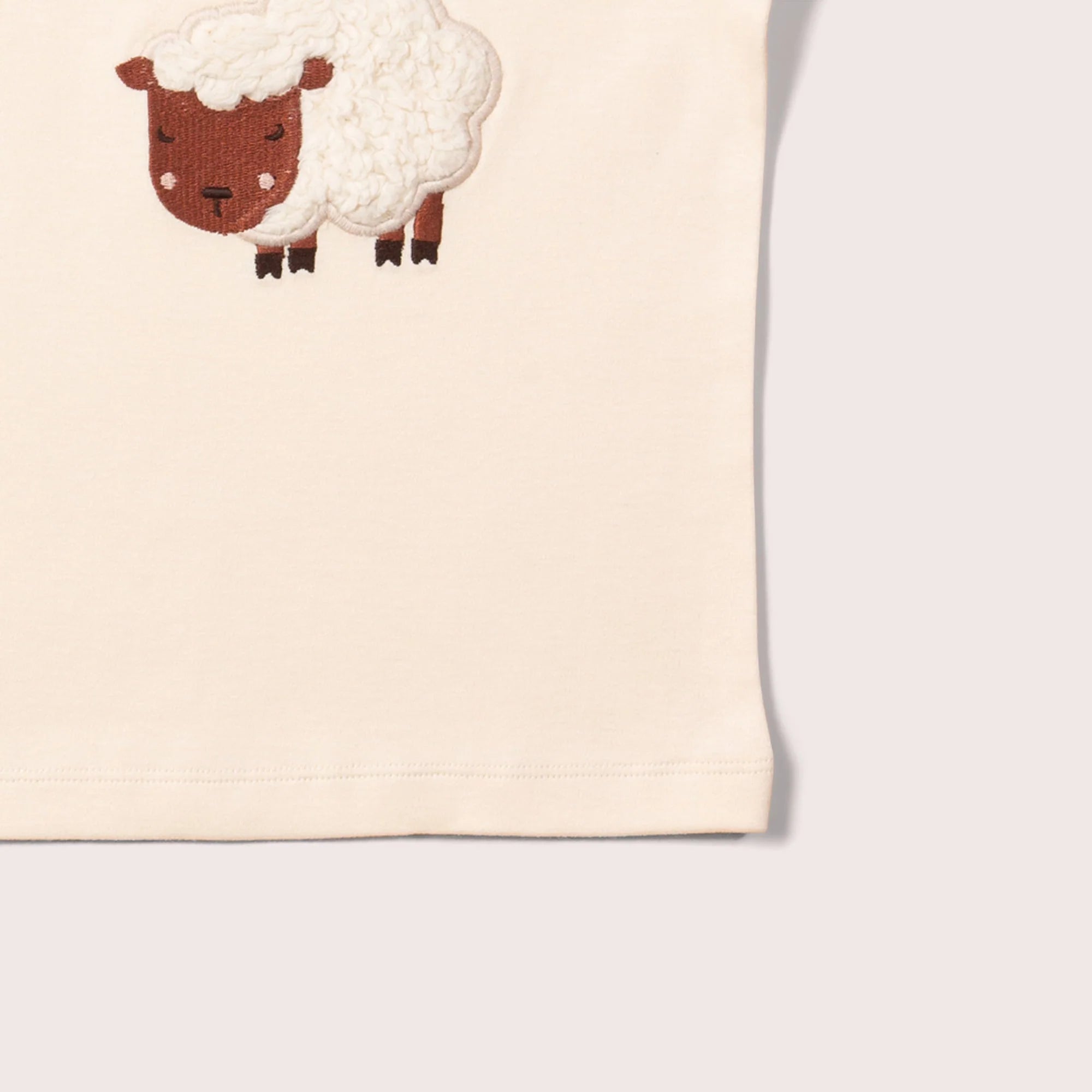 Cream-colored shirt with embroidered fluffy sheep applique.