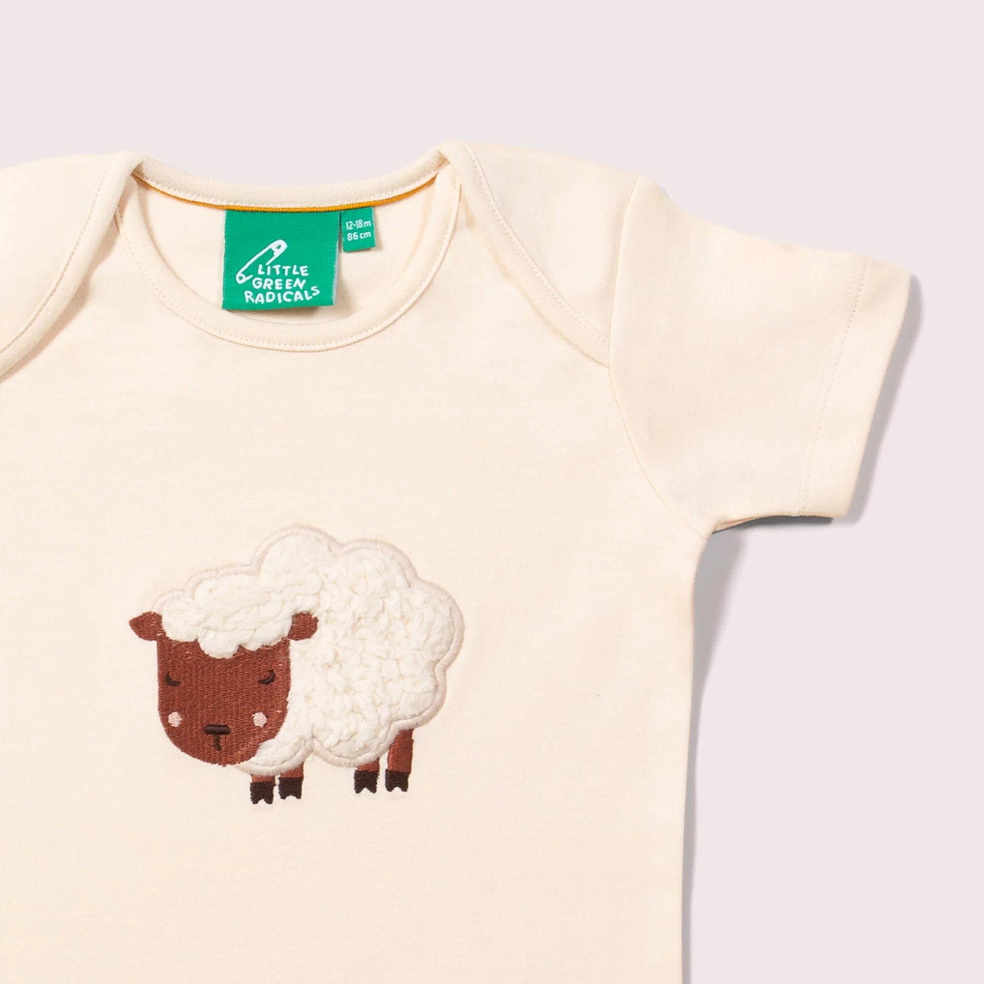 Cream-colored baby bodysuit with short sleeves and an embroidered sheep design.