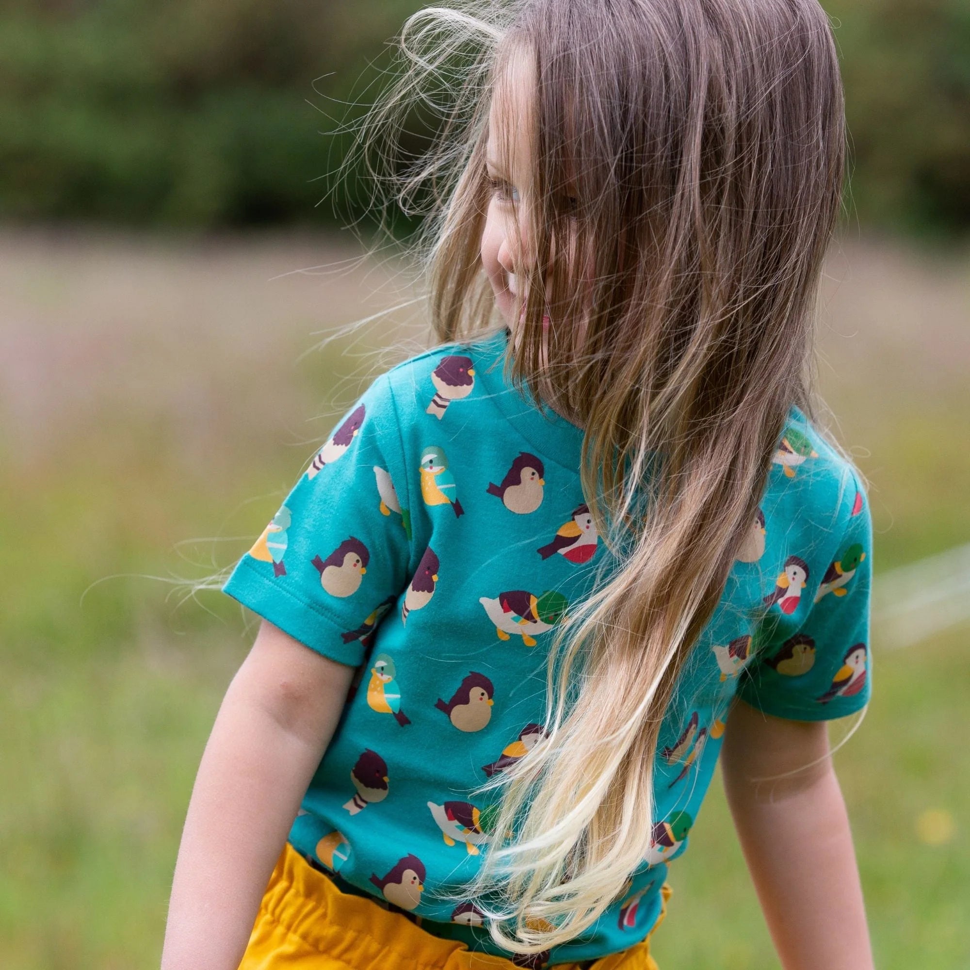 Teal children's short-sleeved t-shirt with a whimsical bird pattern.