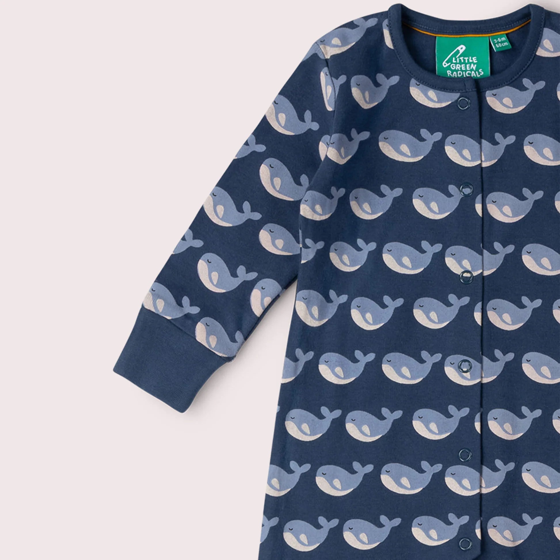 Navy baby onesie with whale pattern on a light pink background