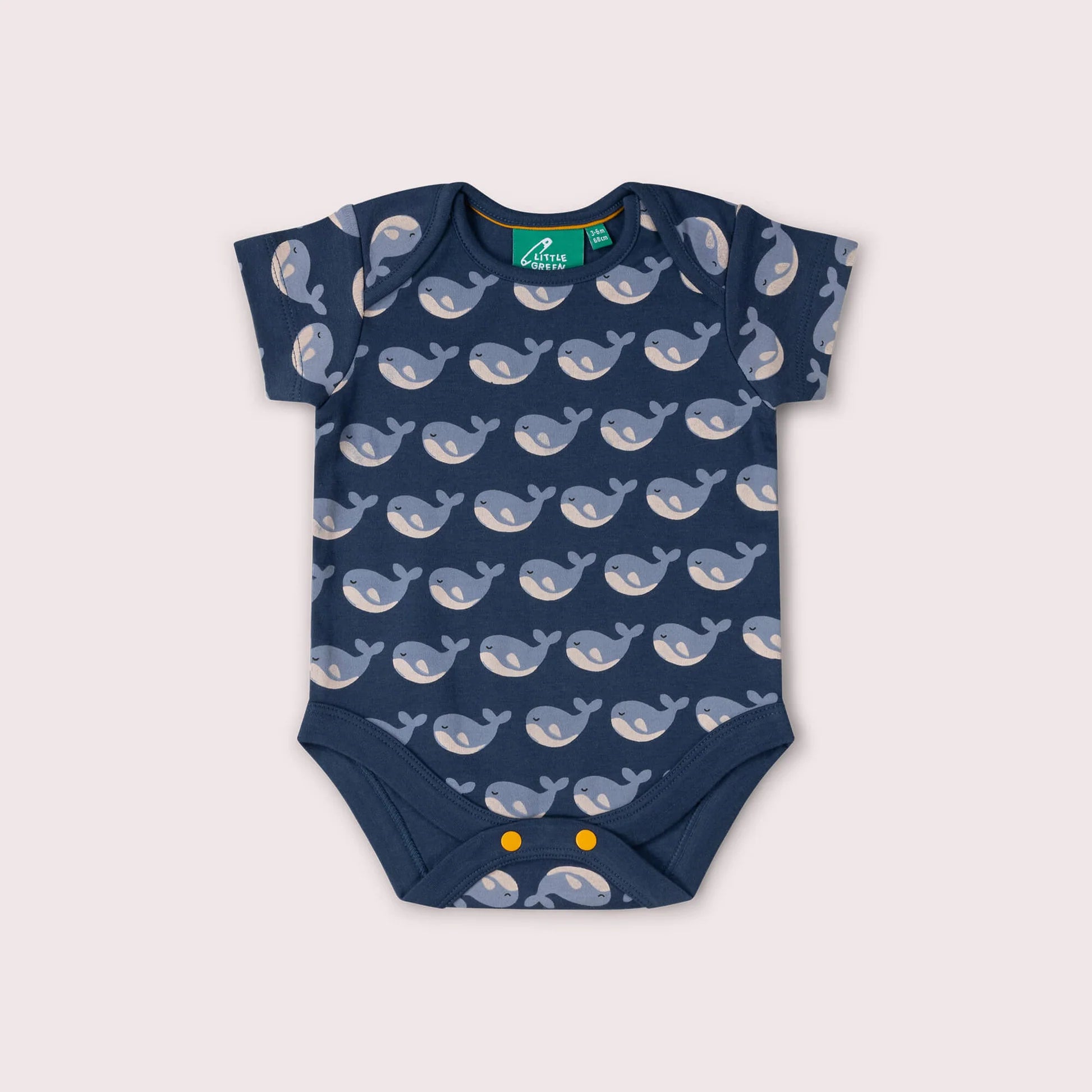 Navy blue baby onesie with whale pattern on a light gray background