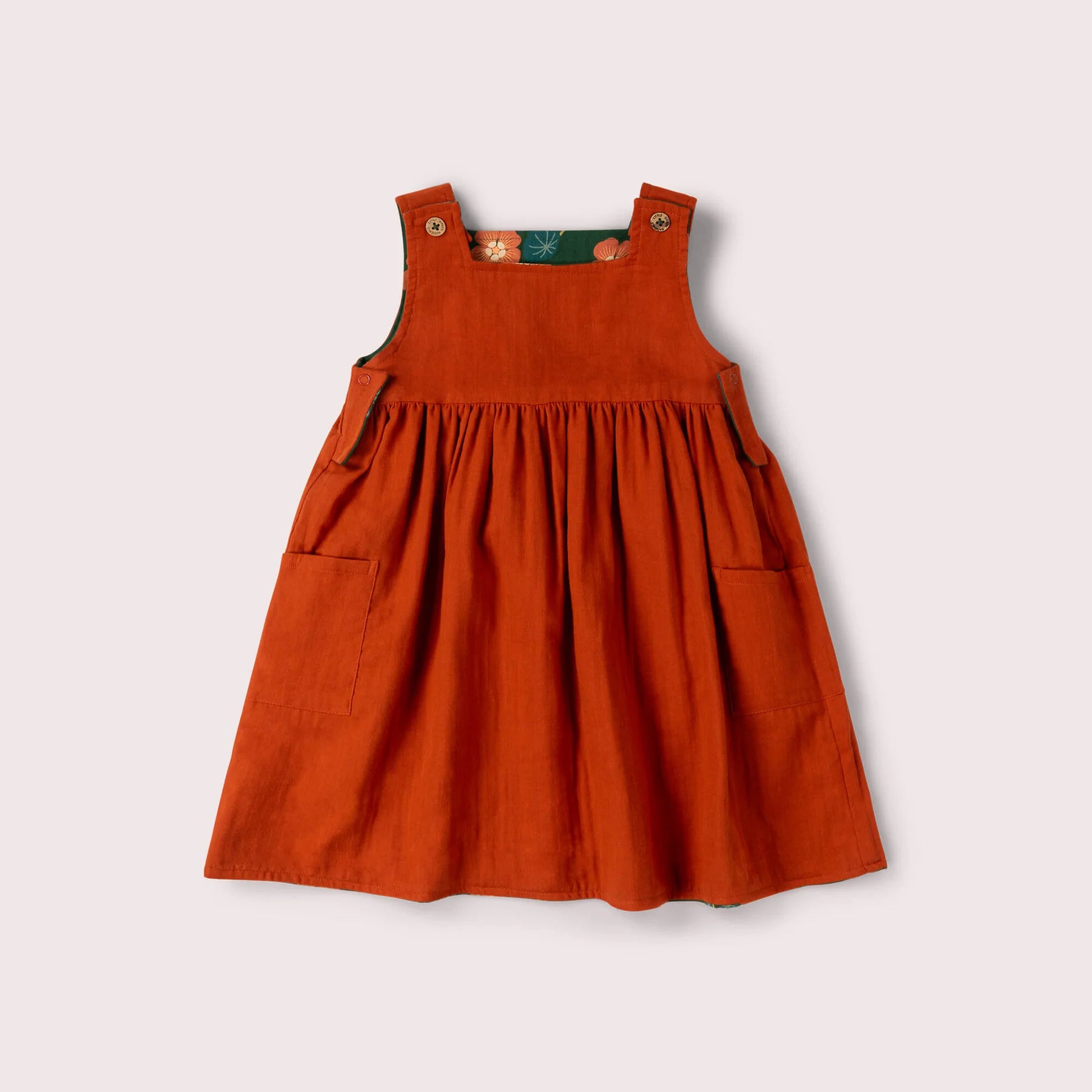 Orange pinafore dress on a light gray background