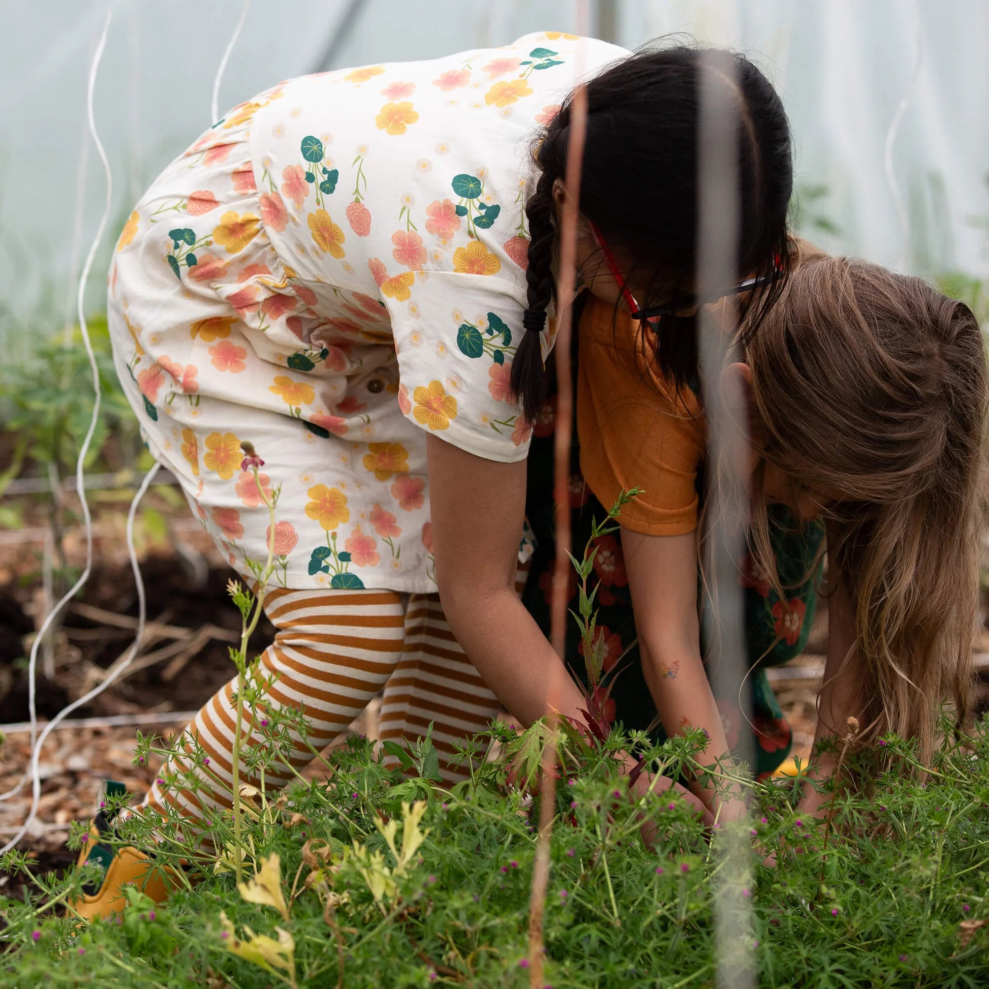 Two children gardening together in a greenhouse