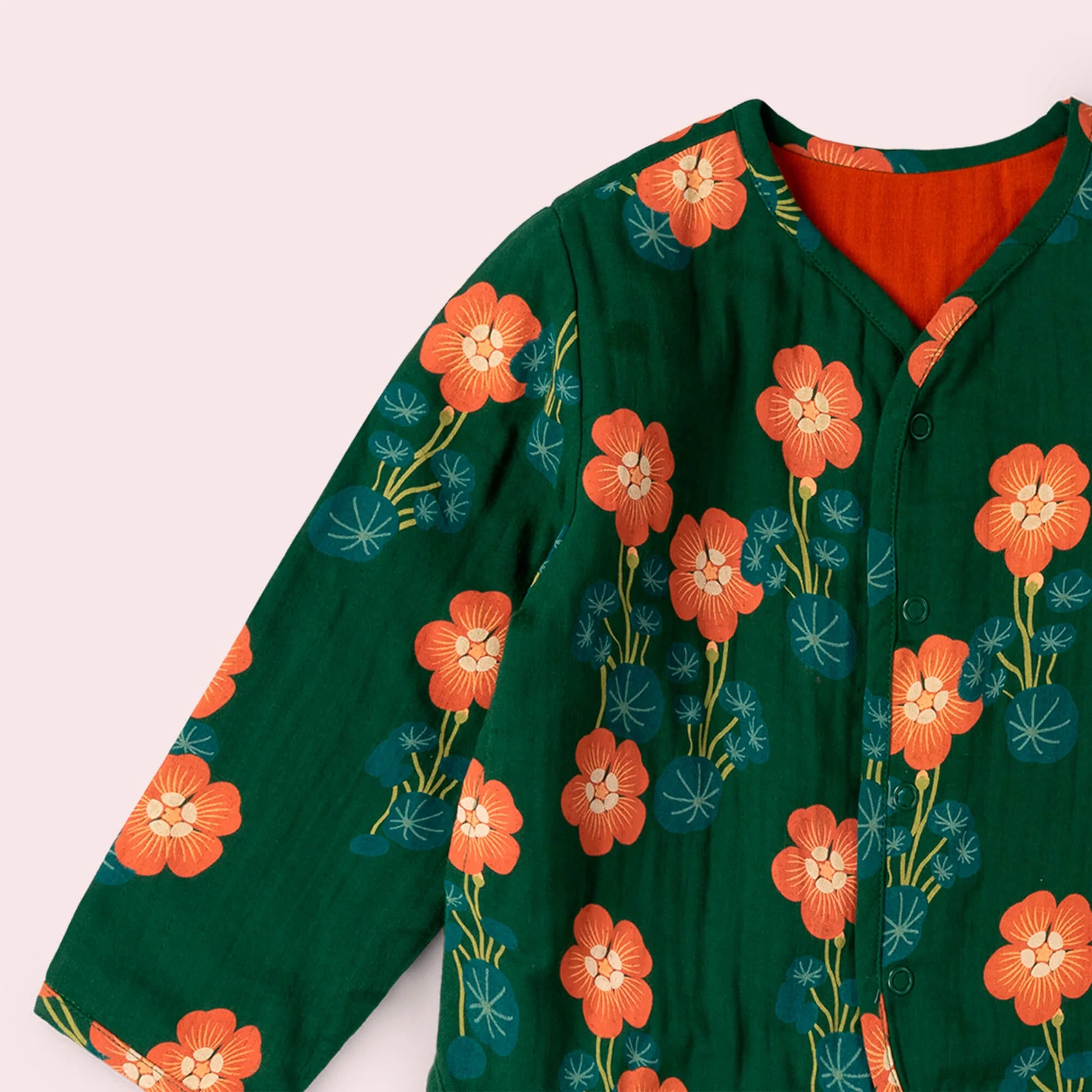 Green shirt with orange floral pattern on a light pink background