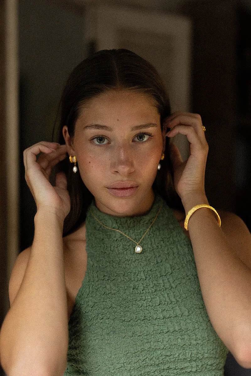 Woman adjusting earrings with a blurred background