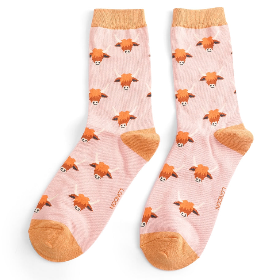 Pair of pink socks with a repeating pattern of Highland cow faces.