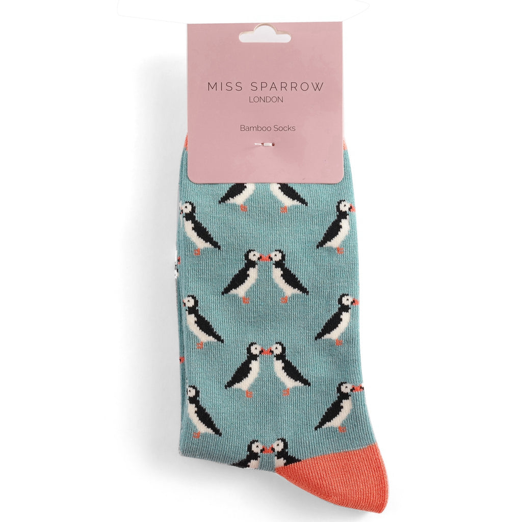 Pair of teal bamboo socks featuring a repeating pattern of kissing puffins.  Coral-colored heel and toe.