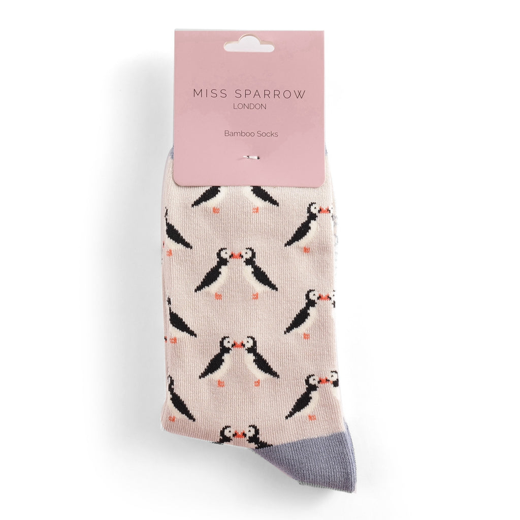 Pair of light beige bamboo socks featuring a repeating pattern of kissing puffins.