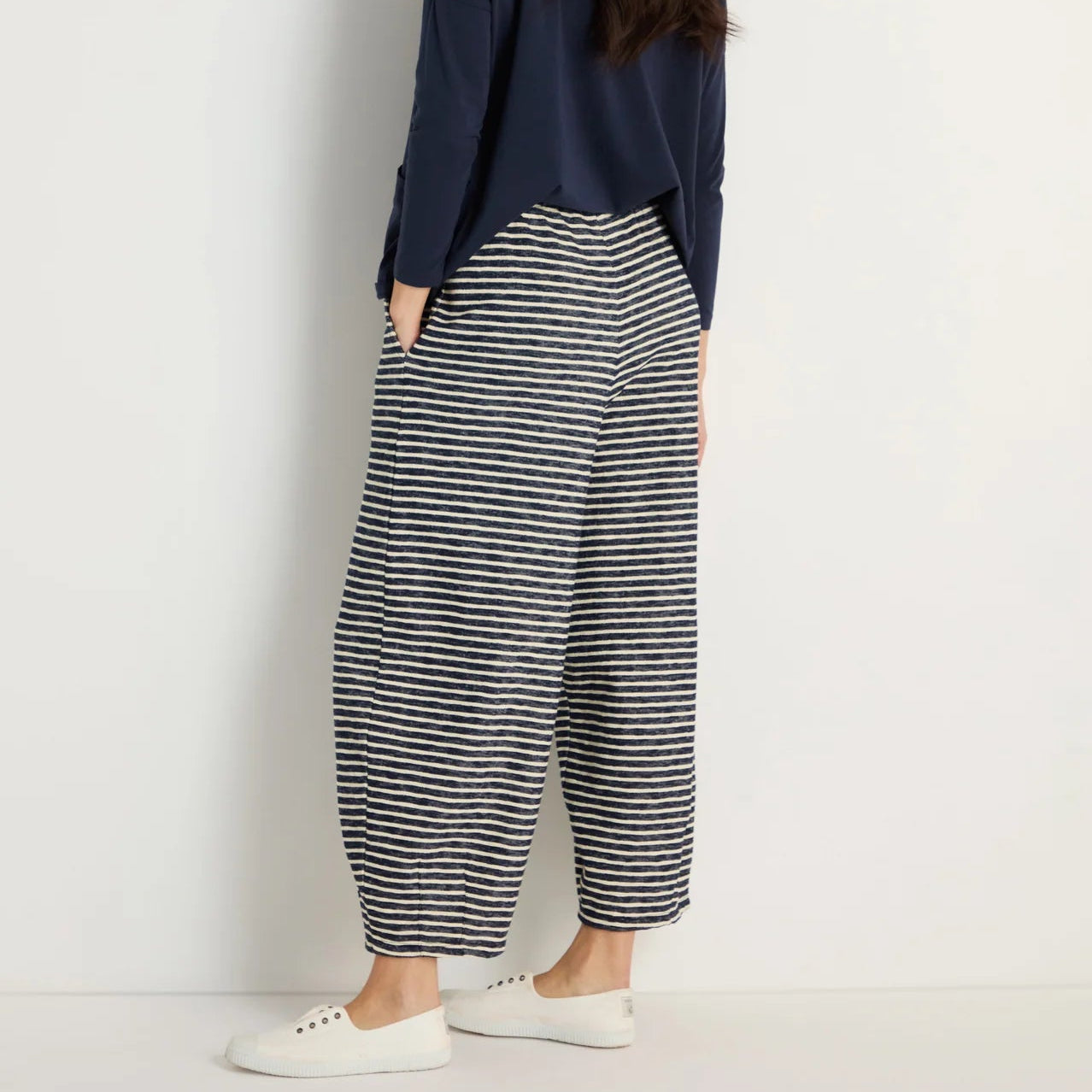 Women wearing wide leg thin striped navy and off white trousers. styled with a simple navy blue top. 