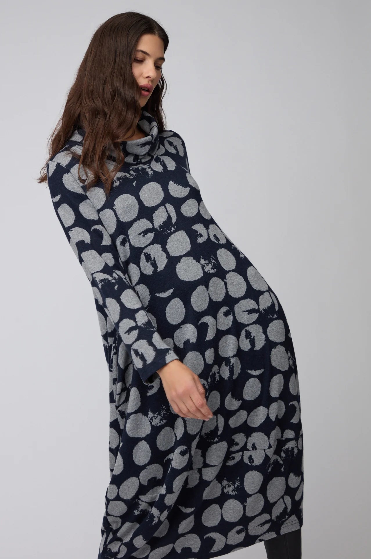 Woman wearing a long, dark blue dress with light gray pattern on a white background