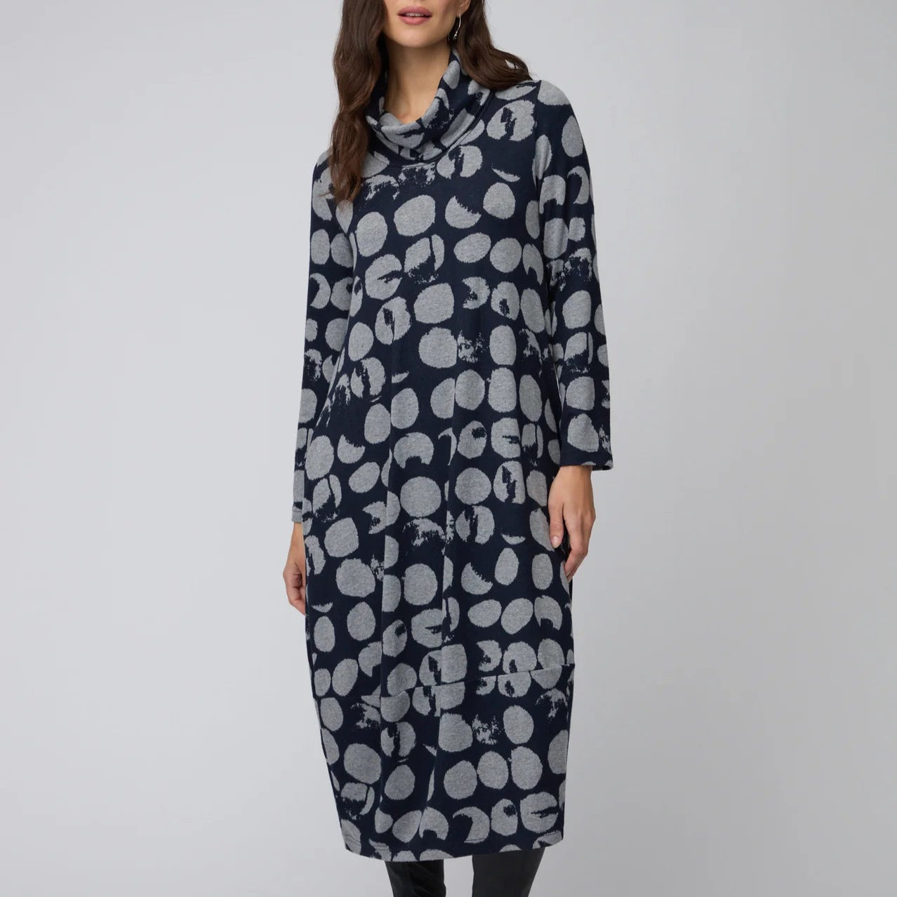 Woman wearing a long, dark blue dress with a white floral pattern on a light gray background