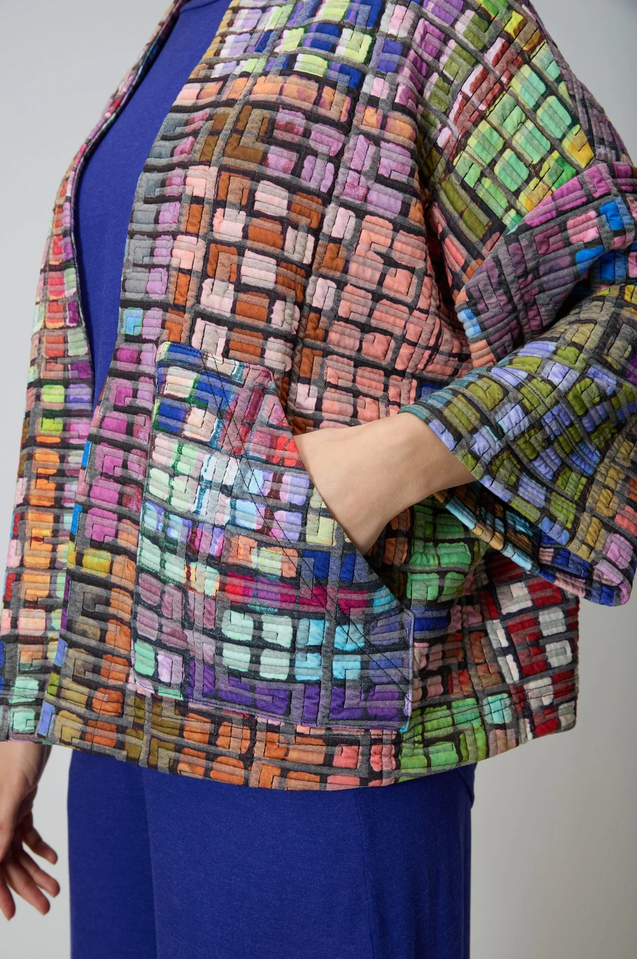 Multicolored textured jacket worn by a person on a plain background