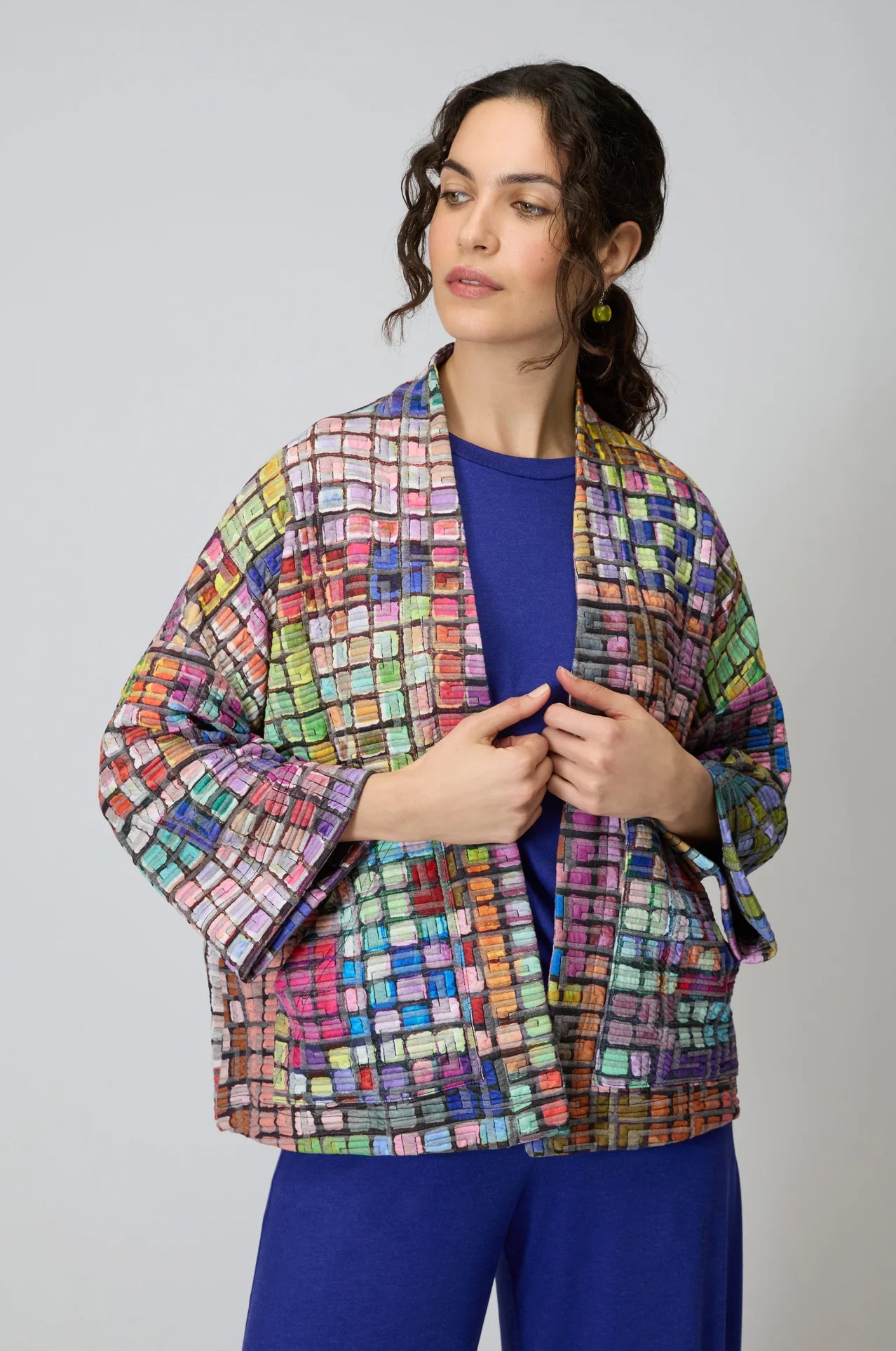 Woman wearing a colorful patterned jacket against a plain background