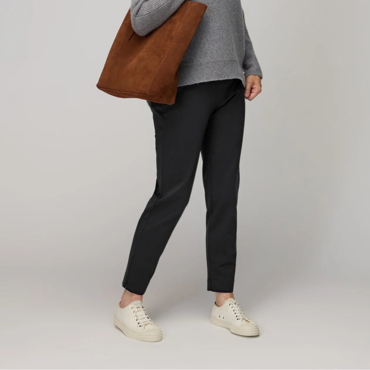 Woman holding a brown tote bag against a plain background