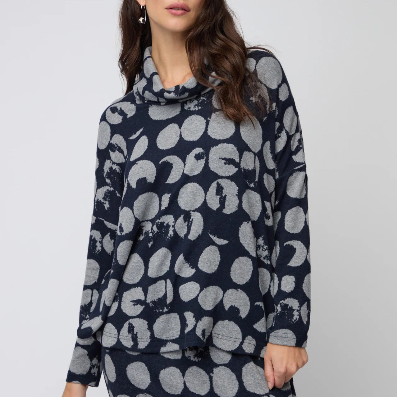 Navy blue sweater with gray abstract pattern worn by a person on a light gray background