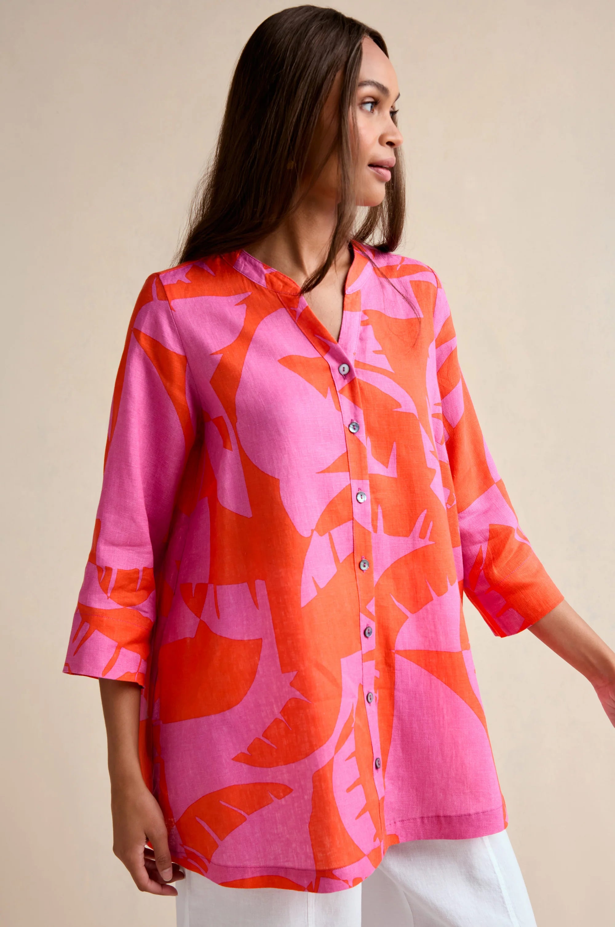 Woman wearing a pink and orange floral blouse against a beige background