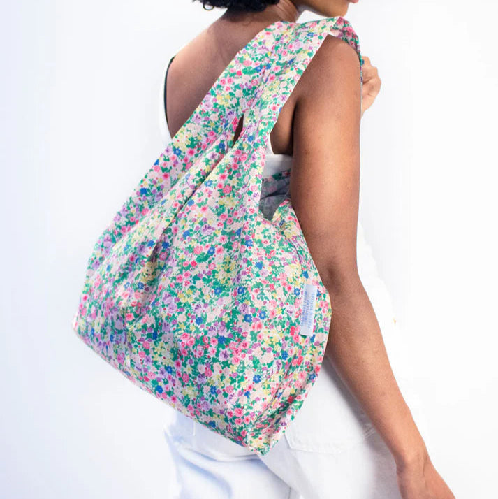 Reusable shopping bag with a floral print.  Multicolored small flowers on a light background.  The bag is folded.