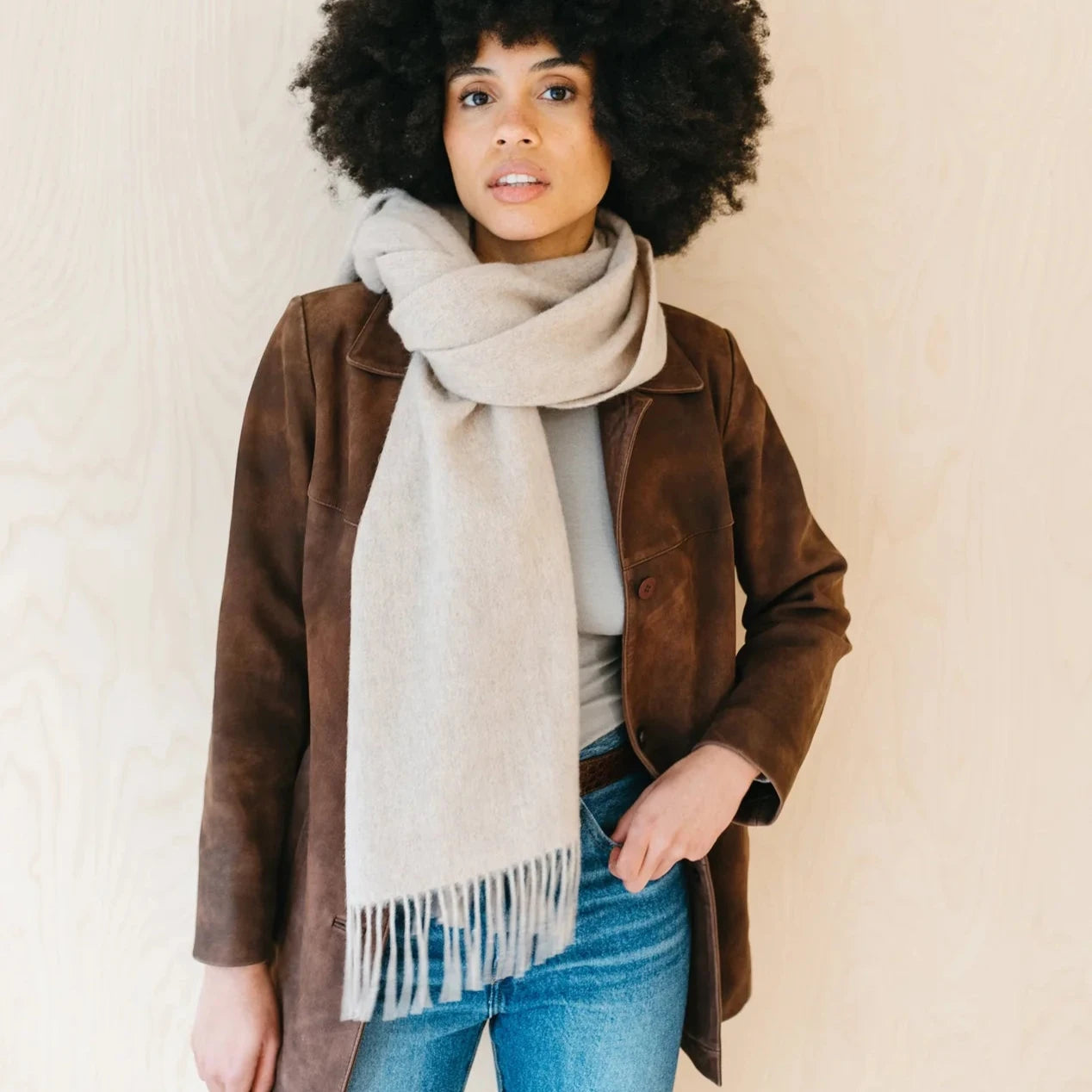 Light beige fringed wool scarf draped around a woman's neck.