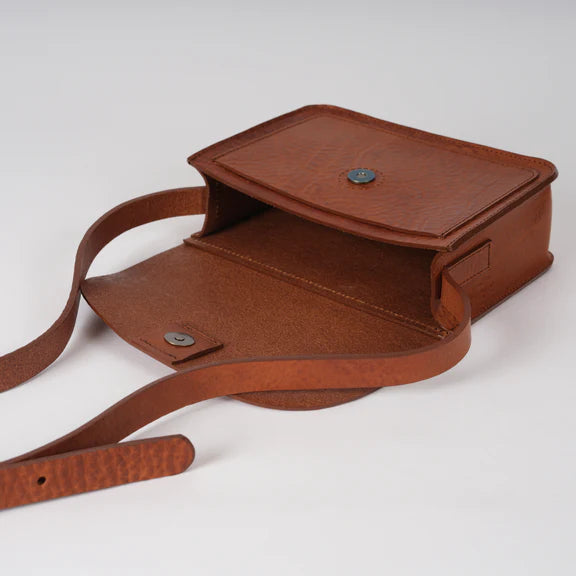Brown leather crossbody bag with a flap closure and adjustable strap.  The bag is open, showing its interior.