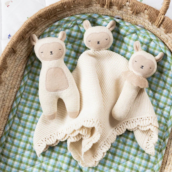 Three knitted toys shaped like a llama, bear, and bunny on a green and blue checkered blanket.