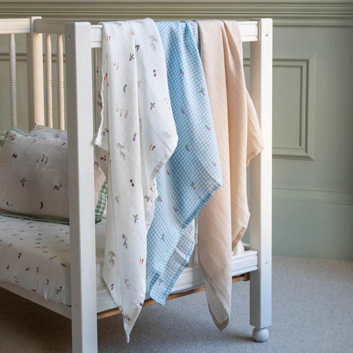 White crib with patterned bedding in a neutral-colored room