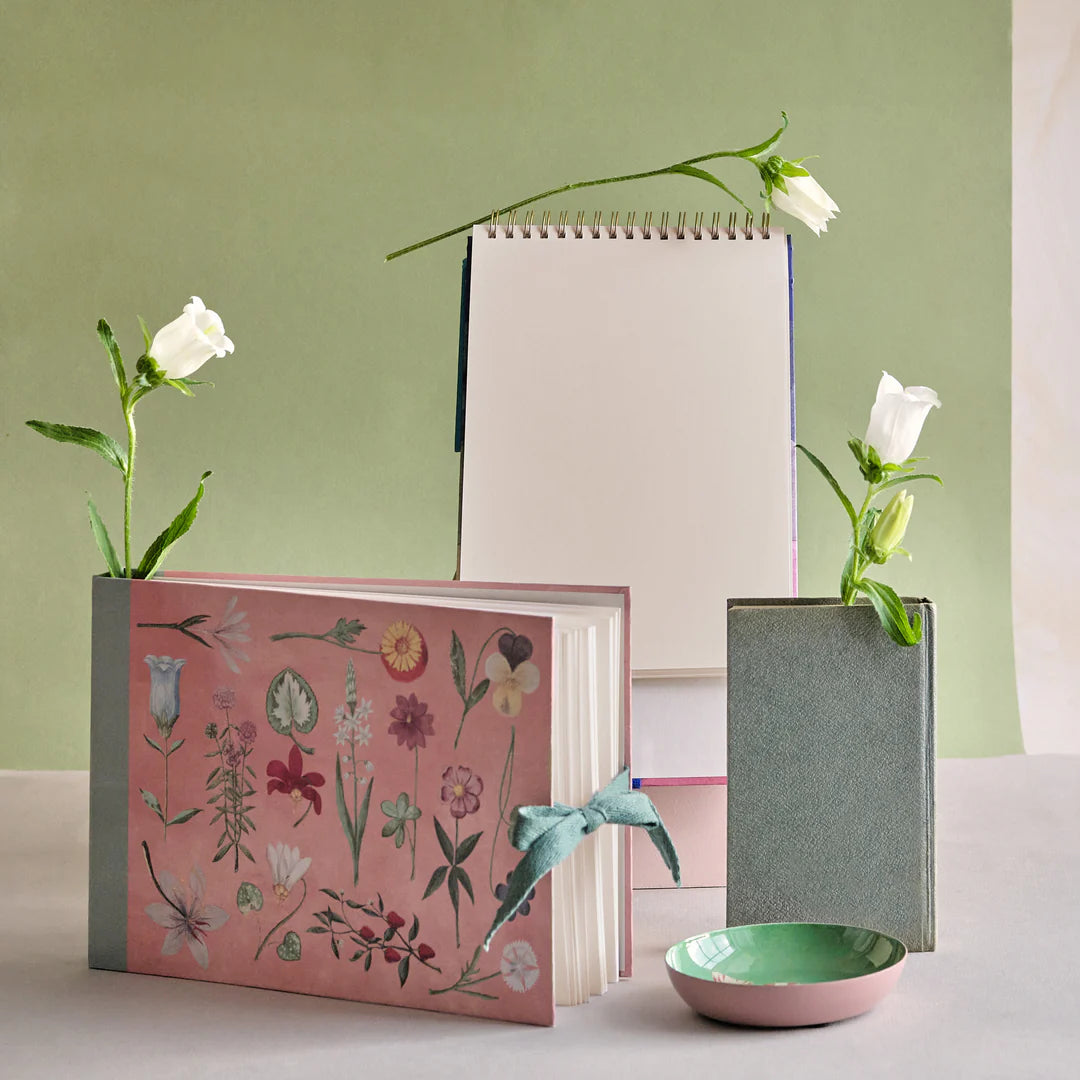 Three notebooks with floral designs and white flowers on a light green background