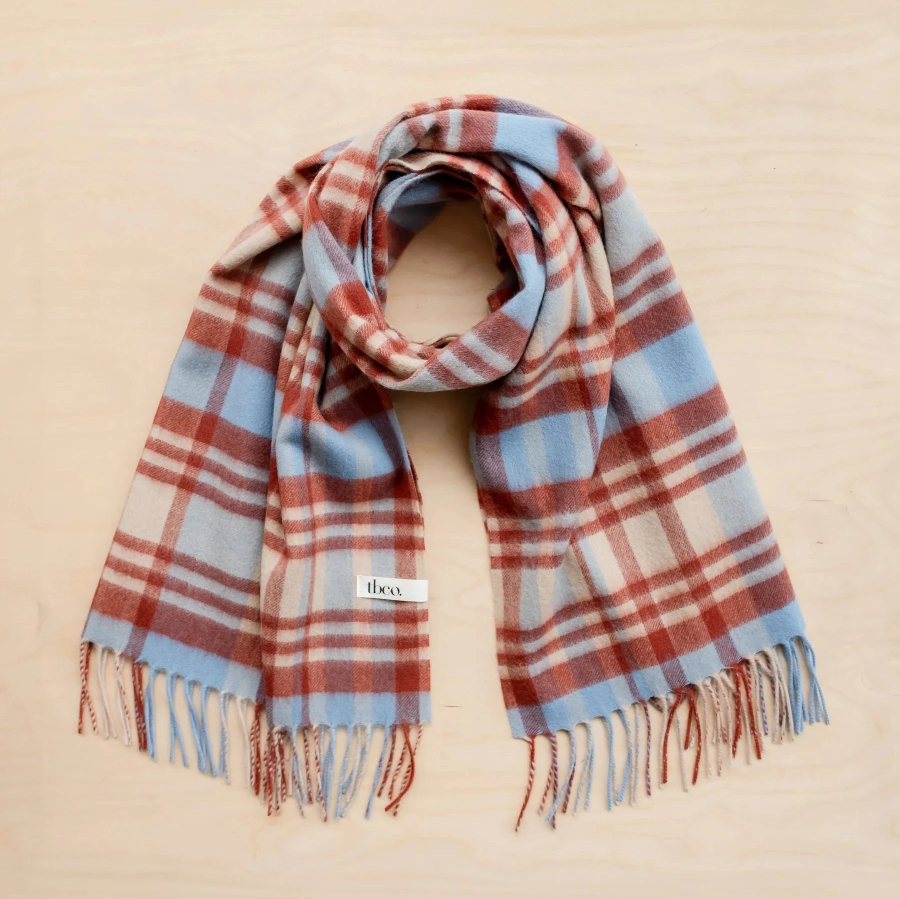 Soft, fringed plaid scarf in dusty blue, rust, and beige.