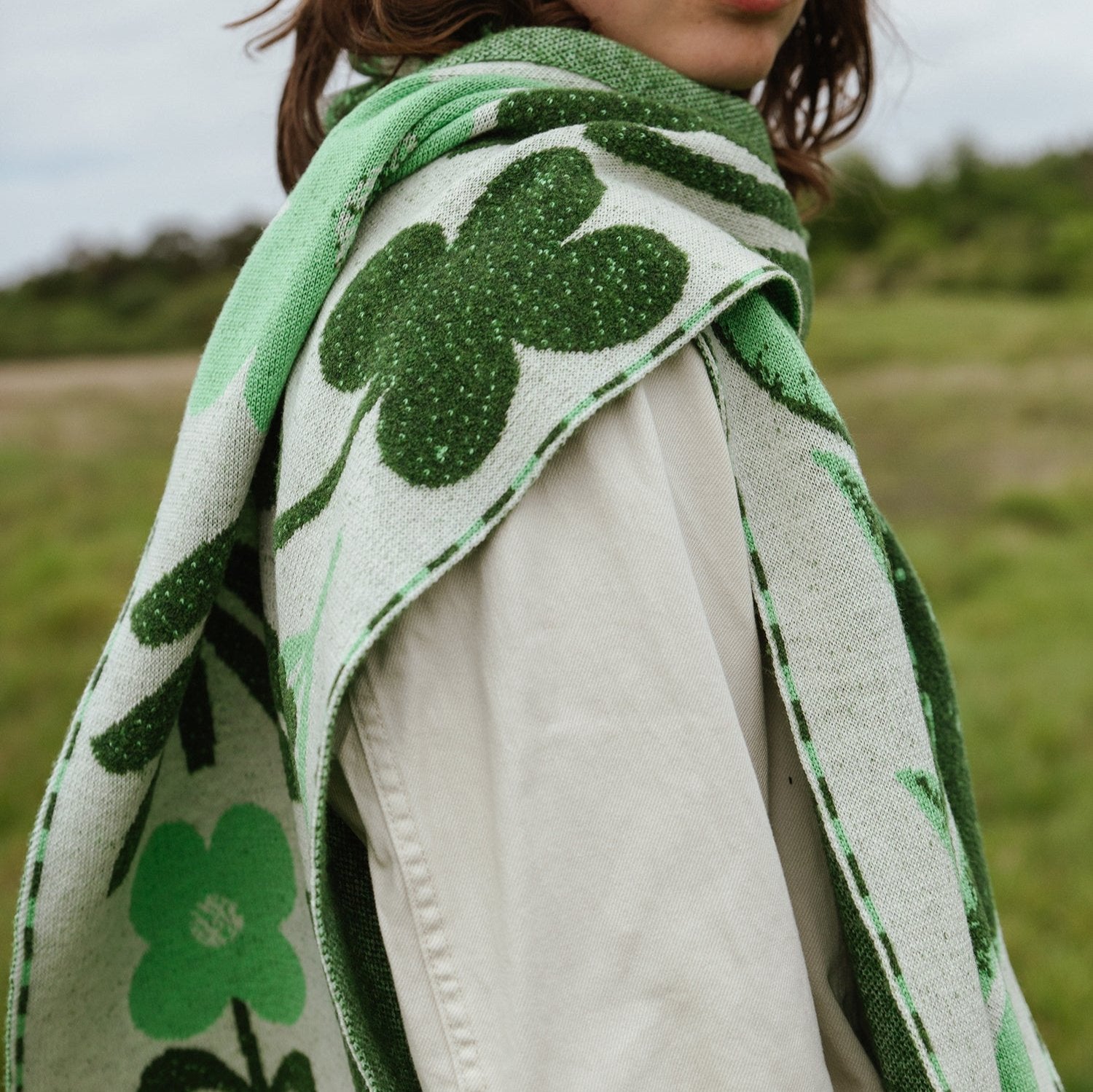 Green and cream knit scarf with a cloverleaf pattern.