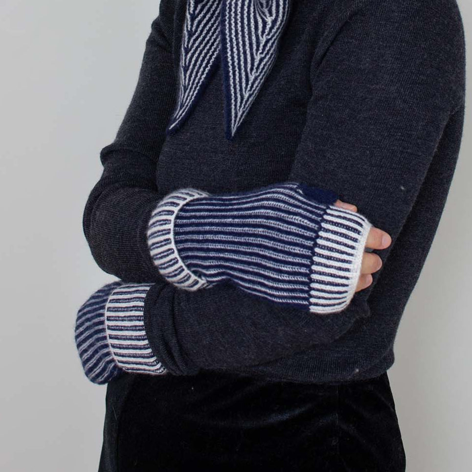 A person wearing navy fingerless gloves with a striped pattern on the cuffs.
